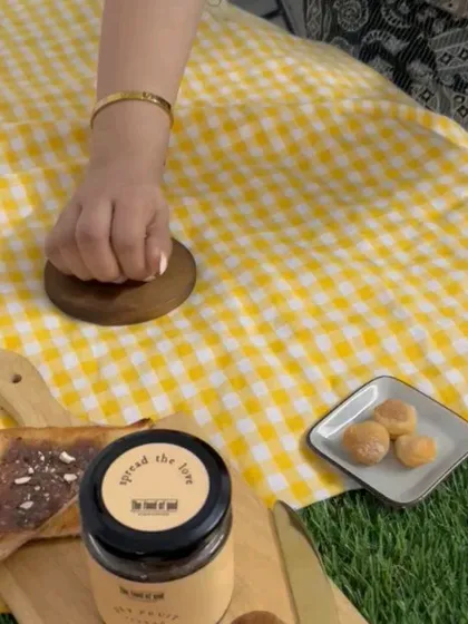 Styling a picnic scene, with a team member placing props on the checkered cloth.