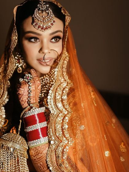 A beautiful portrait of the bride, showcasing her traditional red choora bangles and detailed henna design.
