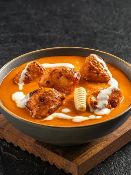 Chicken Tikka Masala, with perfectly cooked chicken in a creamy tomato-based sauce. The image is styled to look hearty and inviting.