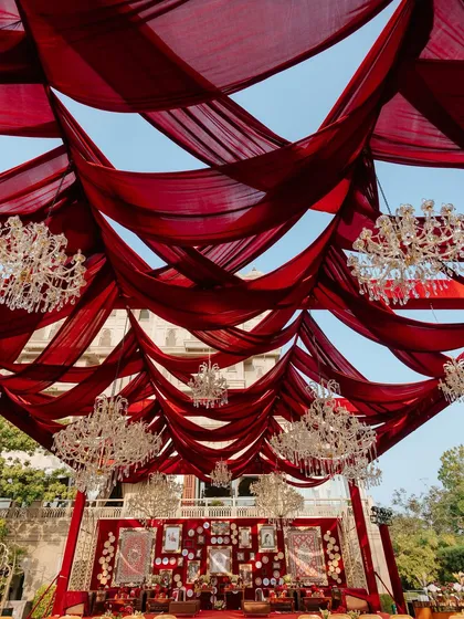 An upward view of the magnificent red fabric ceiling and crystal chandeliers. This element of the 'Laal Ishq' decor added a sense of grandeur and opulence to the entire wedding venue.
