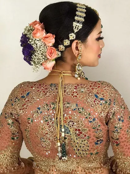 A gorgeous bridal updo with a mix of roses and baby's breath. The hairstyle is designed to look beautiful from every angle.