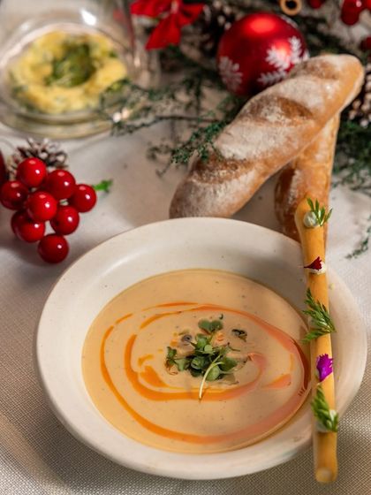 A creamy holiday soup served with a decorated breadstick. Every dish in our festive menu is thoughtfully presented.