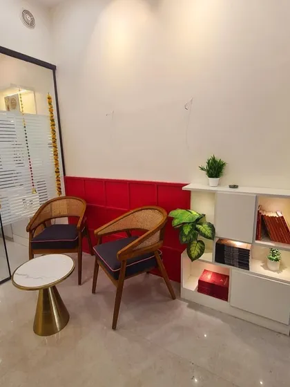 The waiting area for my clients. I wanted to create a peaceful and comfortable waiting area for my clients. The red accent wall adds a touch of warmth and energy, while the seating is arranged for a relaxed experience before our consultation.