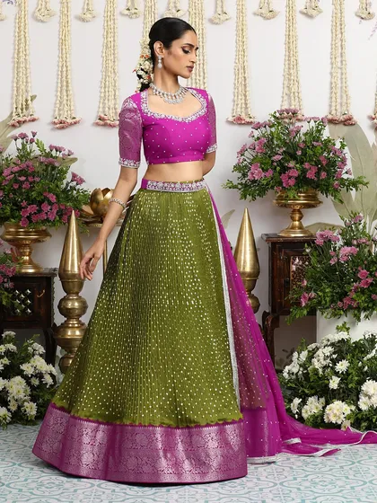 An unconventional yet stunning combination of an olive green Bandhani lehenga with a magenta embroidered blouse and a pink silk brocade border.