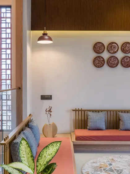 The seating area is defined by a beautiful arrangement of low wooden furniture, terracotta-colored cushions, and a patterned jali screen that filters light.