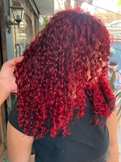 A side view of the fiery red curls, showing the beautiful shape of the cut and the intensity of the color.