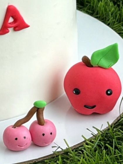 A close-up of the cute, handmade fondant cherries and apple from our fruits-themed cake.