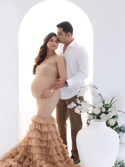 A tender moment between the parents-to-be. The dad's gentle kiss and embrace beautifully complement the mom's serene expression in this minimalist studio setup.