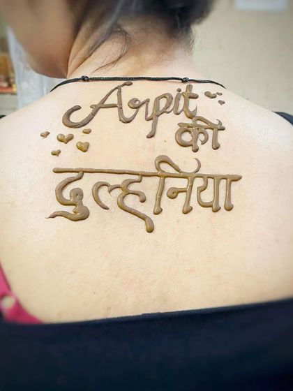 A fun and unique back mehndi design for the bride, saying 'Arpit ki Dulhaniya' (Arpit's Bride). A playful way to make a statement.