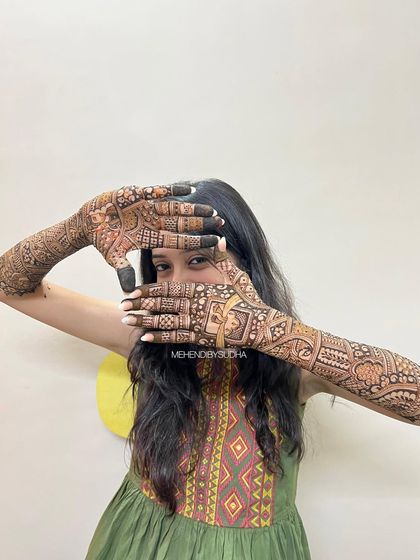 A creative pose framing the bride's face with her beautifully adorned hands.