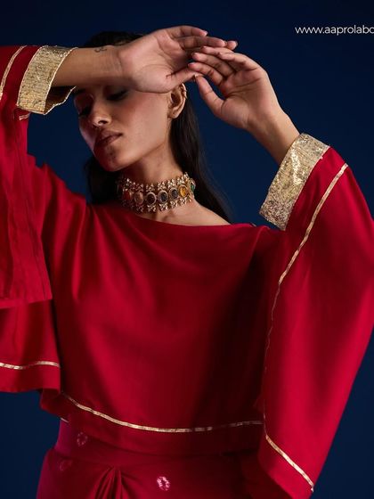 A close-up on the Kimaya Draped Skirt Set by Aapro, highlighting the cape-like sleeves and gold trim.
