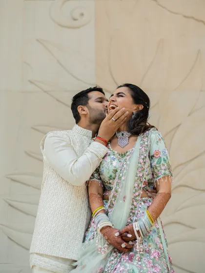 A playful and affectionate moment from a Mehendi function. His spontaneous kiss on her cheek brings out a beautiful, genuine laugh.