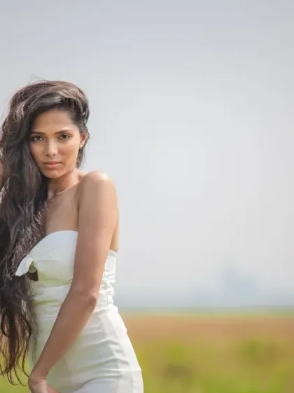 A beautiful bridal fashion shot with a wide-open background. The focus is entirely on the model, her flowing hair, and the simple elegance of her dress.