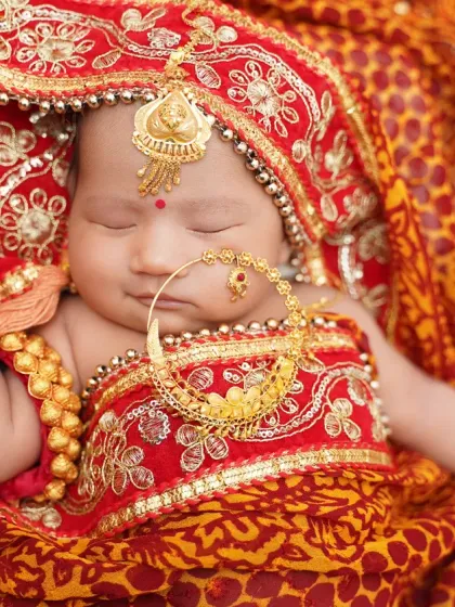 A stunning newborn portrait with a traditional Indian theme. The rich colors of the fabric and intricate jewelry make this a truly unique and beautiful photo.