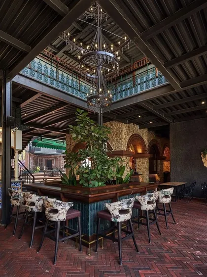 For the interior of Street 1522, I integrated this large, mature tree as the centerpiece of the main bar. This brings the outdoors in, creating a unique biophilic design element that contrasts with the rustic brick and industrial-style chandelier, making the bar a memorable destination within the venue.