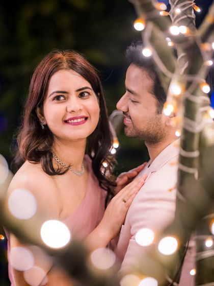 A close-up, intimate portrait framed by the out-of-focus fairy lights, creating a dreamy and artistic effect.