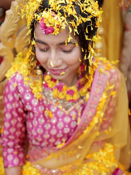 A close-up of the bride covered in flower petals during her Haldi, capturing a moment of pure bliss.