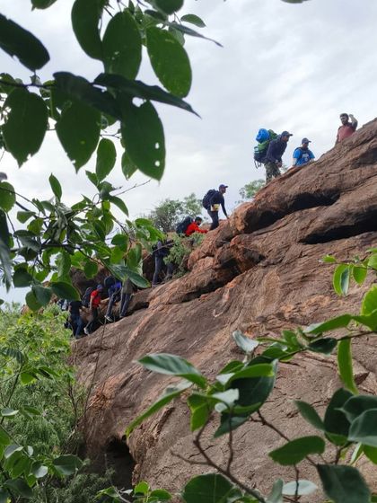 A group of climbers with full packs makes their way along a rocky trail during the approach.