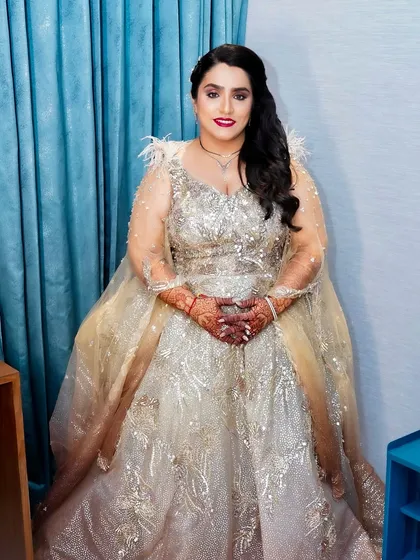 This bride is sparkling for her reception. The glamorous makeup features a bold red lip and defined eyes, matching the drama of her feathered and sequined gown.