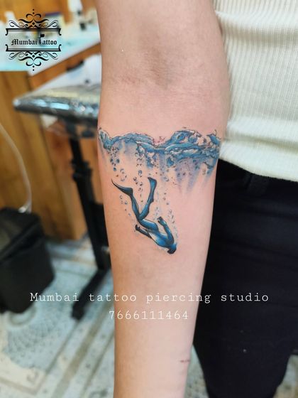 Another look at the artistic diver tattoo. The vibrant blue of the water and the sense of motion make this a truly captivating piece for any ocean lover.