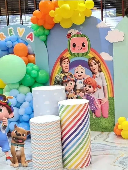 This angle of the Cocomelon party shows the full cast of characters on the backdrop and various themed plinths ready for the cake and desserts.