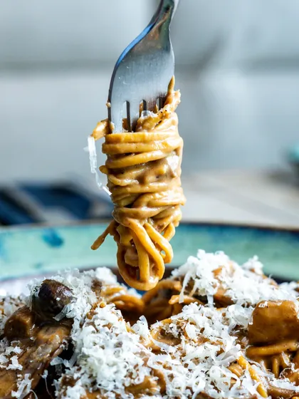 The perfect pasta twirl on a fork, lifted from the plate. This classic shot is all about showcasing the creamy sauce clinging to the noodles, ready to be eaten.