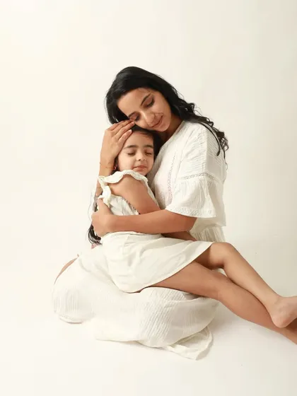 A mother's embrace is the safest place on earth. This serene portrait of a mother holding her daughter close is the epitome of comfort and love.