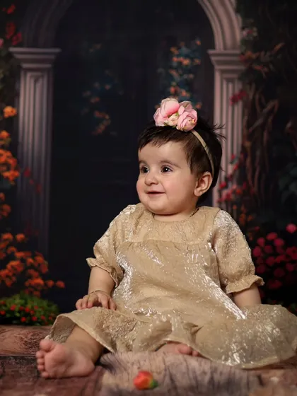 A sweet, happy baby in a golden dress. The simple, elegant backdrop allows her bright personality to be the star of the photo.