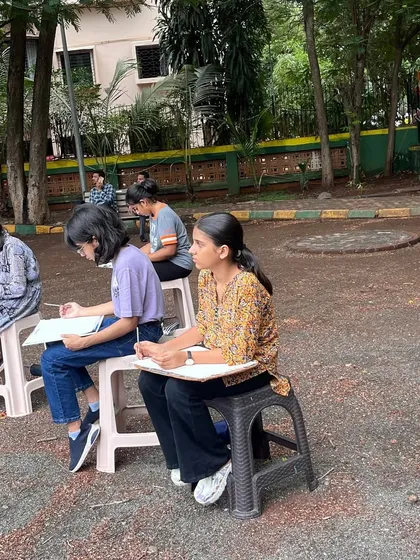 A group of students sketching together outdoors. The shared experience of drawing from life creates a dynamic and supportive learning environment.