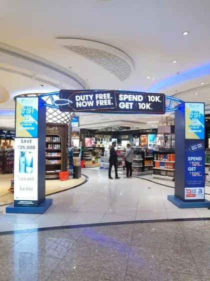 An entrance to the duty-free area featuring promotional arches and digital screens. We capture the full customer journey, including marketing efforts designed to draw people into the store.