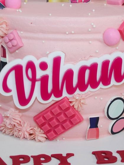 A close-up of the personalized "Vihana" name plaque on the pink themed cake.