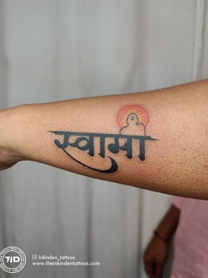 A tribute to Swami Samarth, this tattoo combines his name in Devanagari script with a silhouette of the spiritual master. The setting sun in the background adds a sense of peace and reverence.