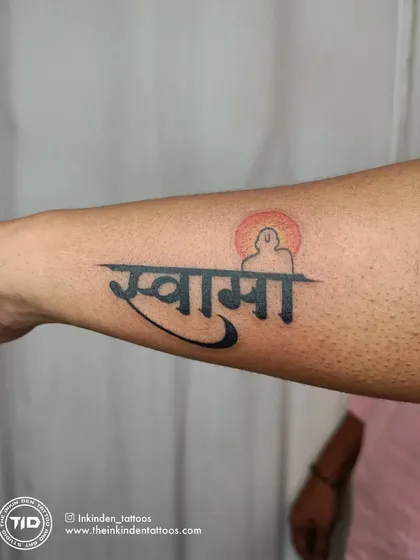 A tribute to Swami Samarth, this tattoo combines his name in Devanagari script with a silhouette of the spiritual master. The setting sun in the background adds a sense of peace and reverence.