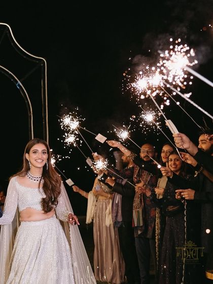 The bride walks through a path of sparklers held by her friends and family. Her joyful expression says it all. This type of interactive entry creates an atmosphere of shared celebration and excitement.