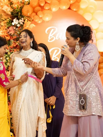 Hosting a beautiful 'Baby in Bloom' baby shower. Here, I'm leading a fun game with the mom-to-be, creating a lighthearted and personal atmosphere. These intimate events are all about celebrating life's precious milestones with warmth and laughter.