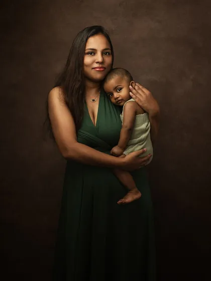 In color, the same portrait feels warm and intimate. The deep, earthy tones of the backdrop and her dress create a rich, painterly effect.