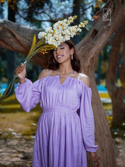 A playful portrait where the model uses a bouquet of flowers as a prop, adding a touch of whimsy to the outdoor fashion shoot.