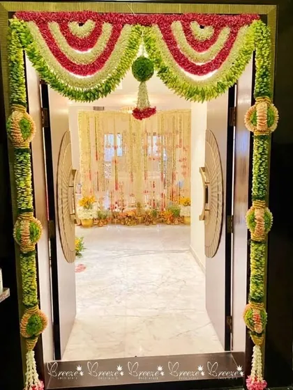 We welcome your guests with beautiful, traditional decor right from the doorstep. This intricate entrance features fresh flower garlands in a classic South Indian style, using jasmine, roses, and green foliage to set a festive tone.