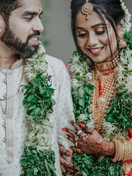 A detailed shot capturing the bride's hand on the groom's arm, highlighting the rich textures of their outfits and the intricate henna design.