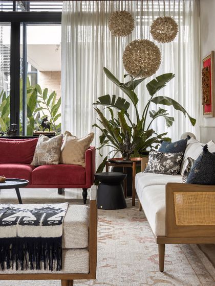 The combination of the red sofa, a caned bench, and textured throws creates a dynamic and inviting seating area.
