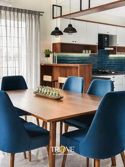 See how our tiles can complete a sophisticated living space. Here, a deep blue subway tile backsplash adds a touch of color and texture to an open concept kitchen and dining area, complementing the modern interior design.