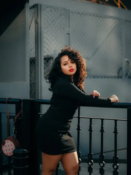 A moody portrait taken on the streets of Bangalore. The cool tones and the model's pose against the railing create a sophisticated and slightly edgy fashion shot.