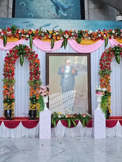 This is a complete stage setup I created for a formal tribute event at ONGC. The design includes a clean white backdrop with draped fabric, multiple floral arches, and professional stage lighting to create a respectful and distinguished ambiance.