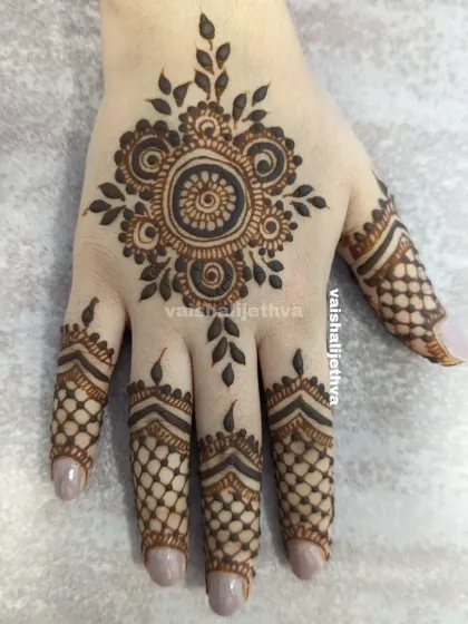 A beautiful back-hand mandala design. The central floral motif is surrounded by delicate leafy patterns, and the fingers have a net-like design.