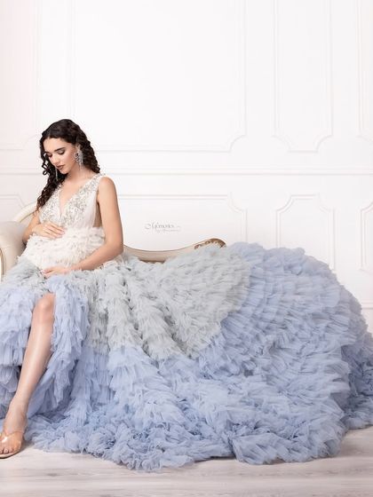 This glow, this moment, this love. A voluminous ruffled gown in soft blue tones creates a dreamy, fairytale-like setting for this beautiful mom-to-be.