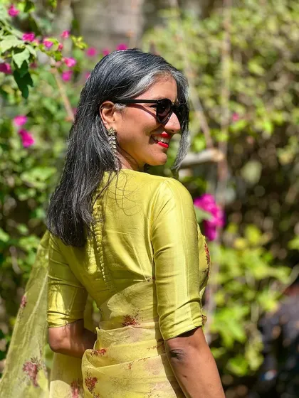 A candid shot from the wedding, showing the beautiful drape of the organza saree. Paired with sunglasses, it’s a modern take on wedding guest attire.
