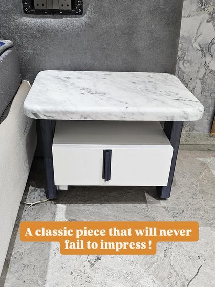 This classic nightstand will never go out of style. It features a white marble top, a sturdy dark frame, and a contrasting white drawer with a sleek black handle.