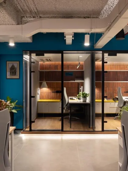 A row of glass-walled private cabins adjacent to an open desk area. This design provides acoustic privacy for focused work while maintaining a visual connection to the rest of the team.