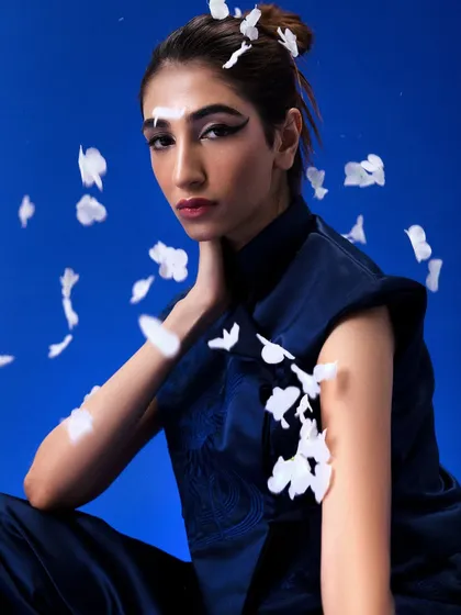 A beautiful shot from the "Yume" editorial with falling petals, highlighting the sharp winged eyeliner and messy top-knot.
