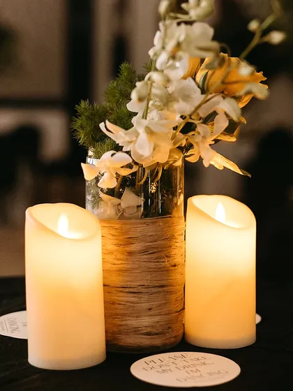 A simple yet elegant centerpiece with candles and a floral arrangement in a twine-wrapped vase, perfect for a rustic-chic theme.